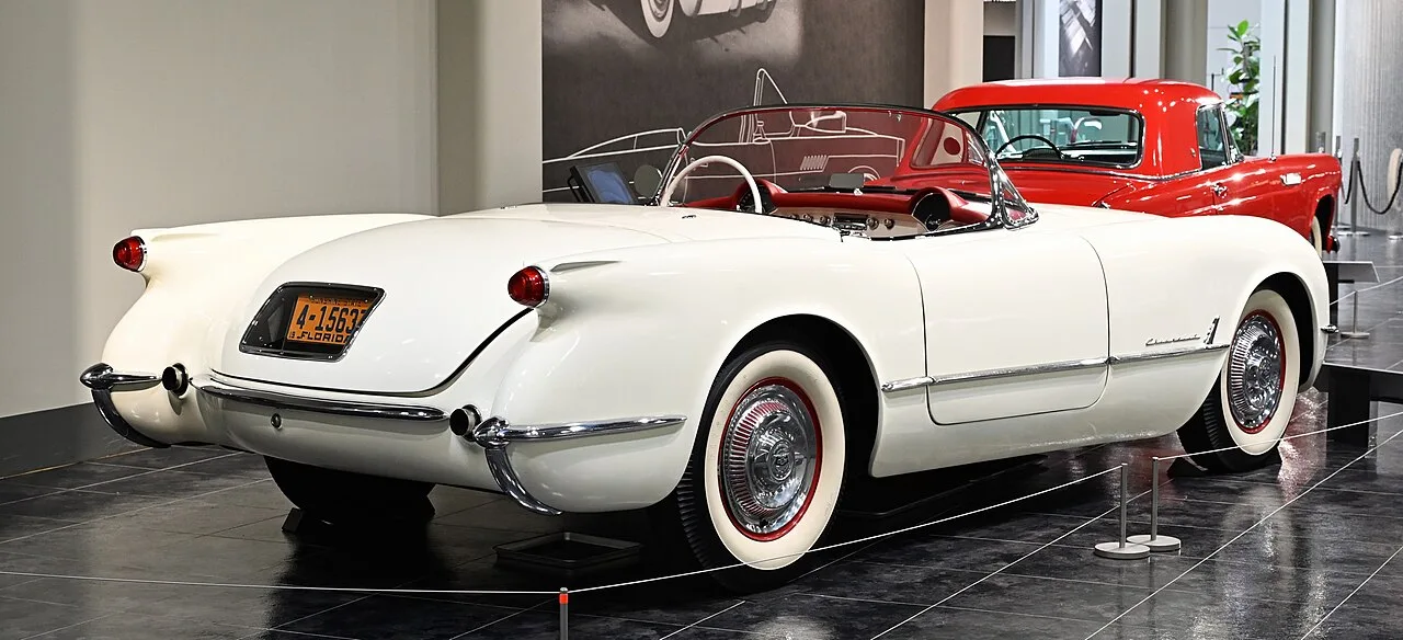 Chevrolet Corvette C1 uit 1956 in rood met chroom sierlijsten, zijaanzicht op een lege weg