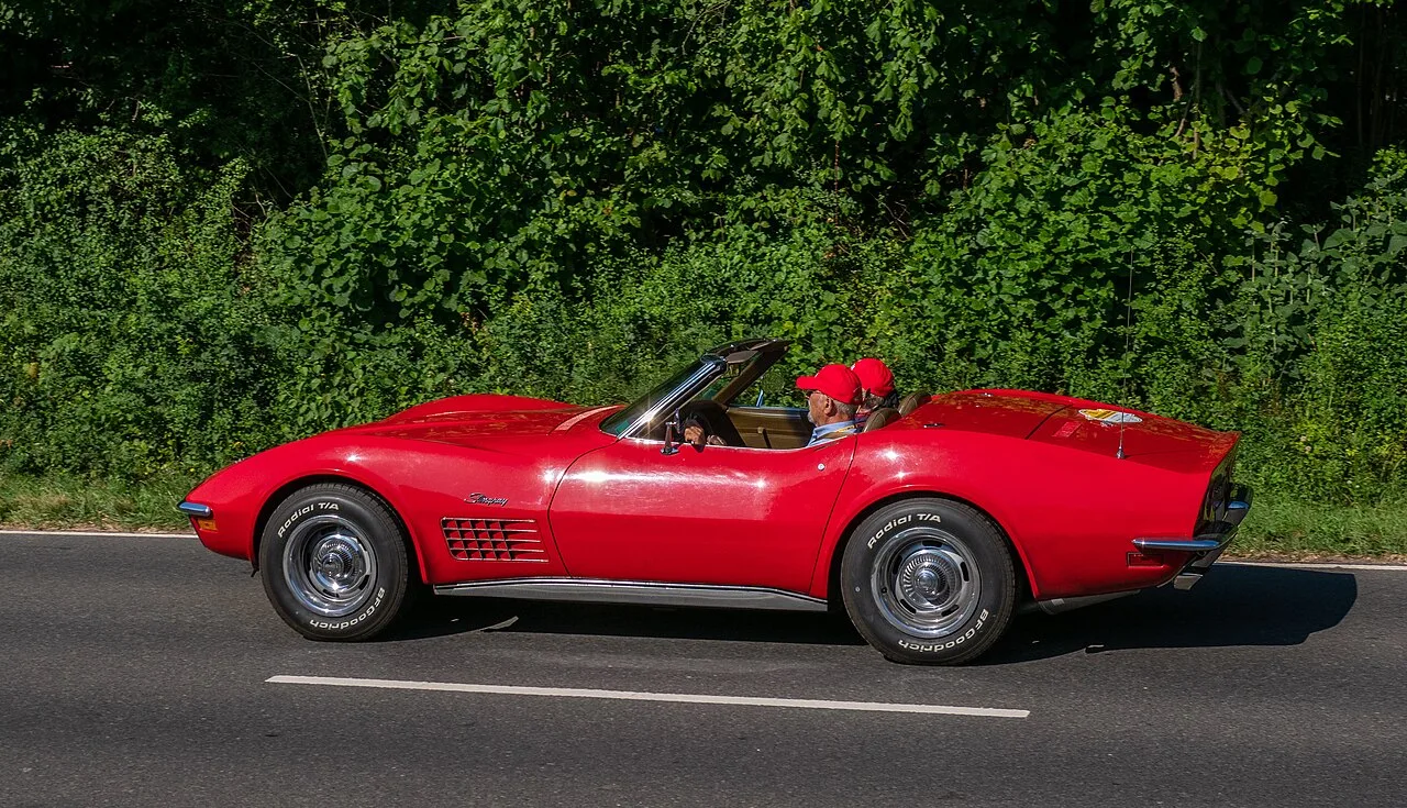 Corvette C3 Convertible 1970 in Daytona Yellow met open dak op zonnige snelweg
