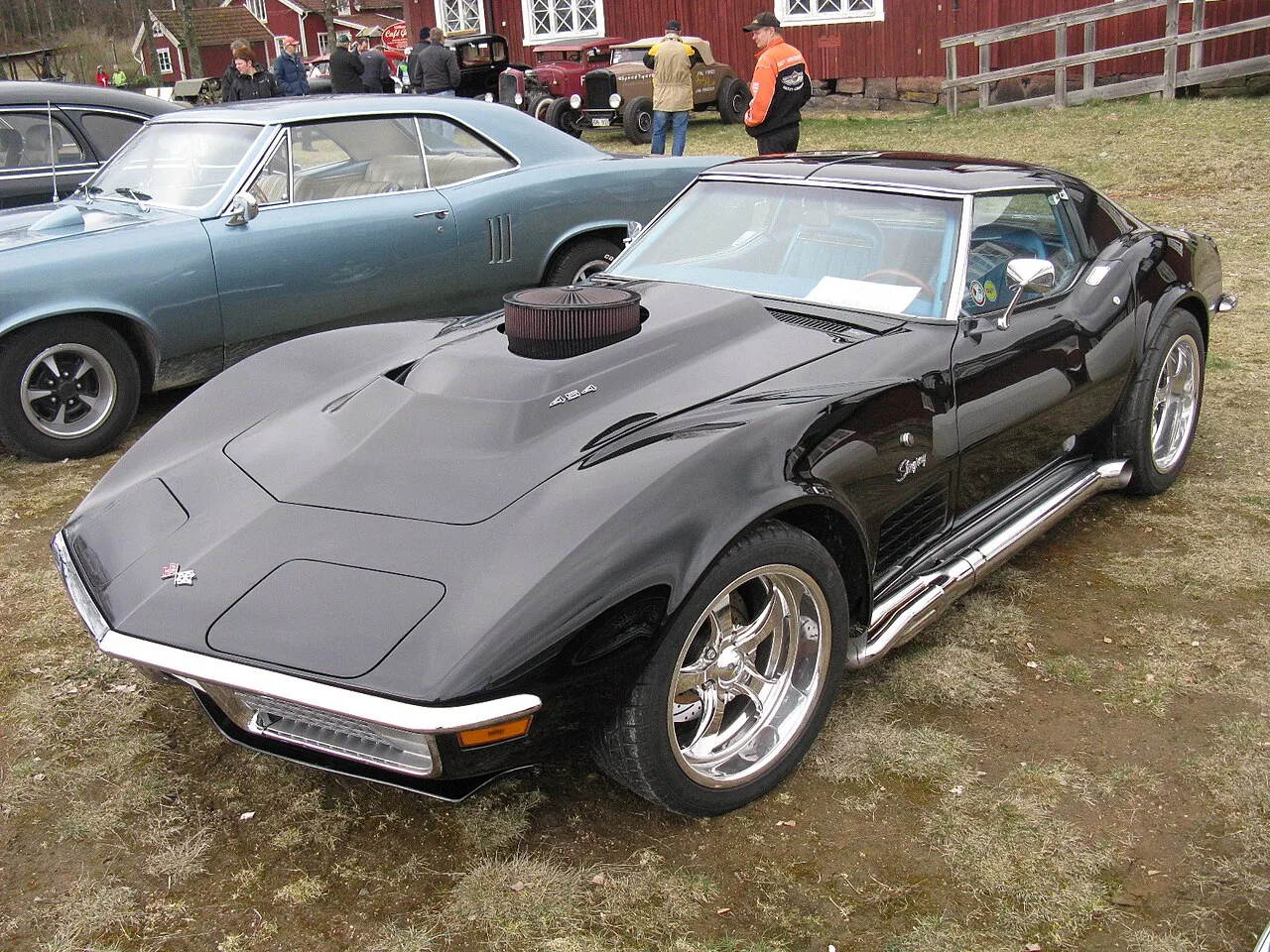 Een zwarte vroege Chevrolet Corvette C3 met 454-motorkapembleem en zijuitlaten