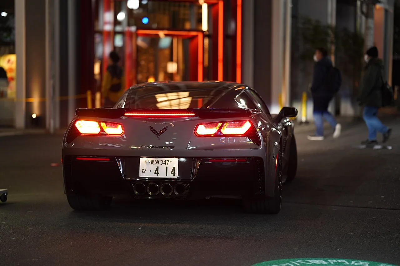 Achteraanzicht van een grijze Chevrolet Corvette C7 bij avond
