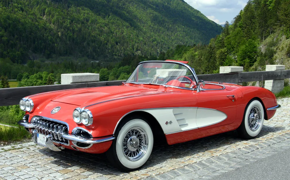 Een rood-witte Chevrolet Corvette C1 uit 1958 met glasfiber carrosserie in een berglandschap