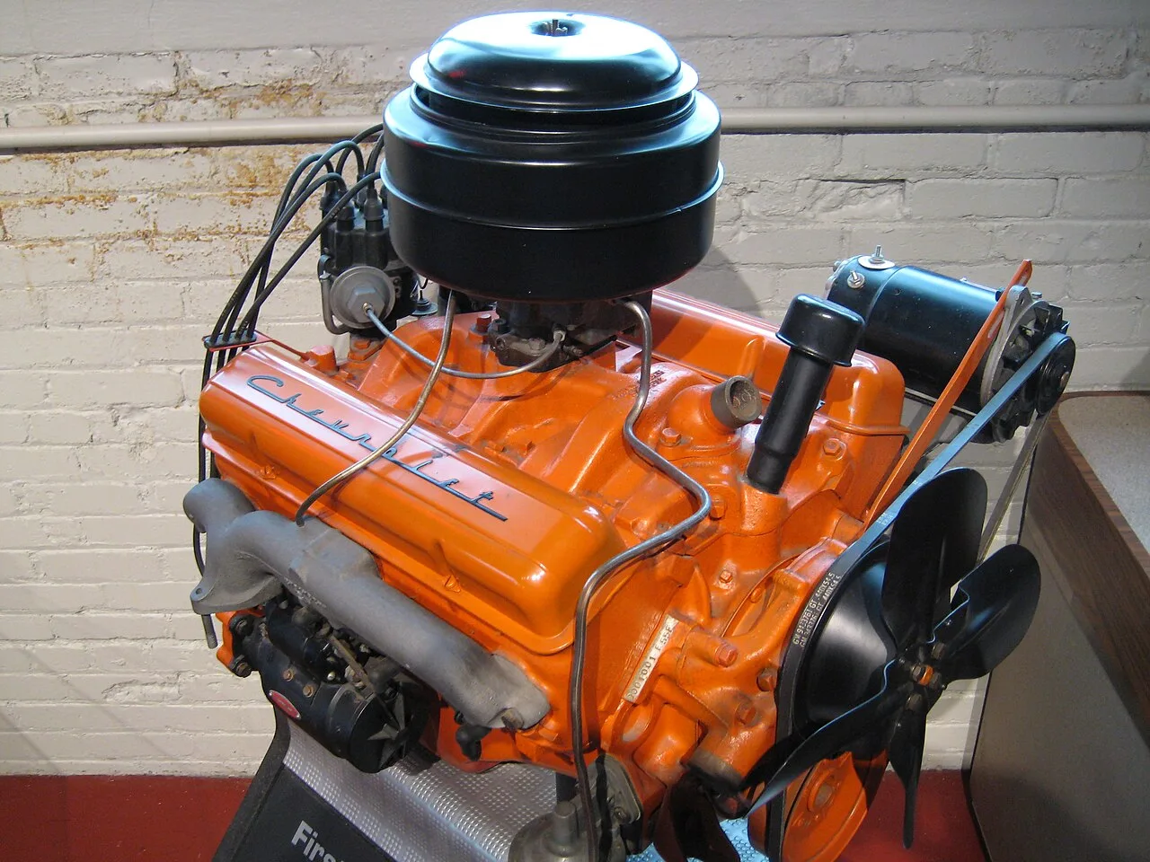 Een oranje Chevrolet small-block V8-motor met luchtfilterhuis op een display