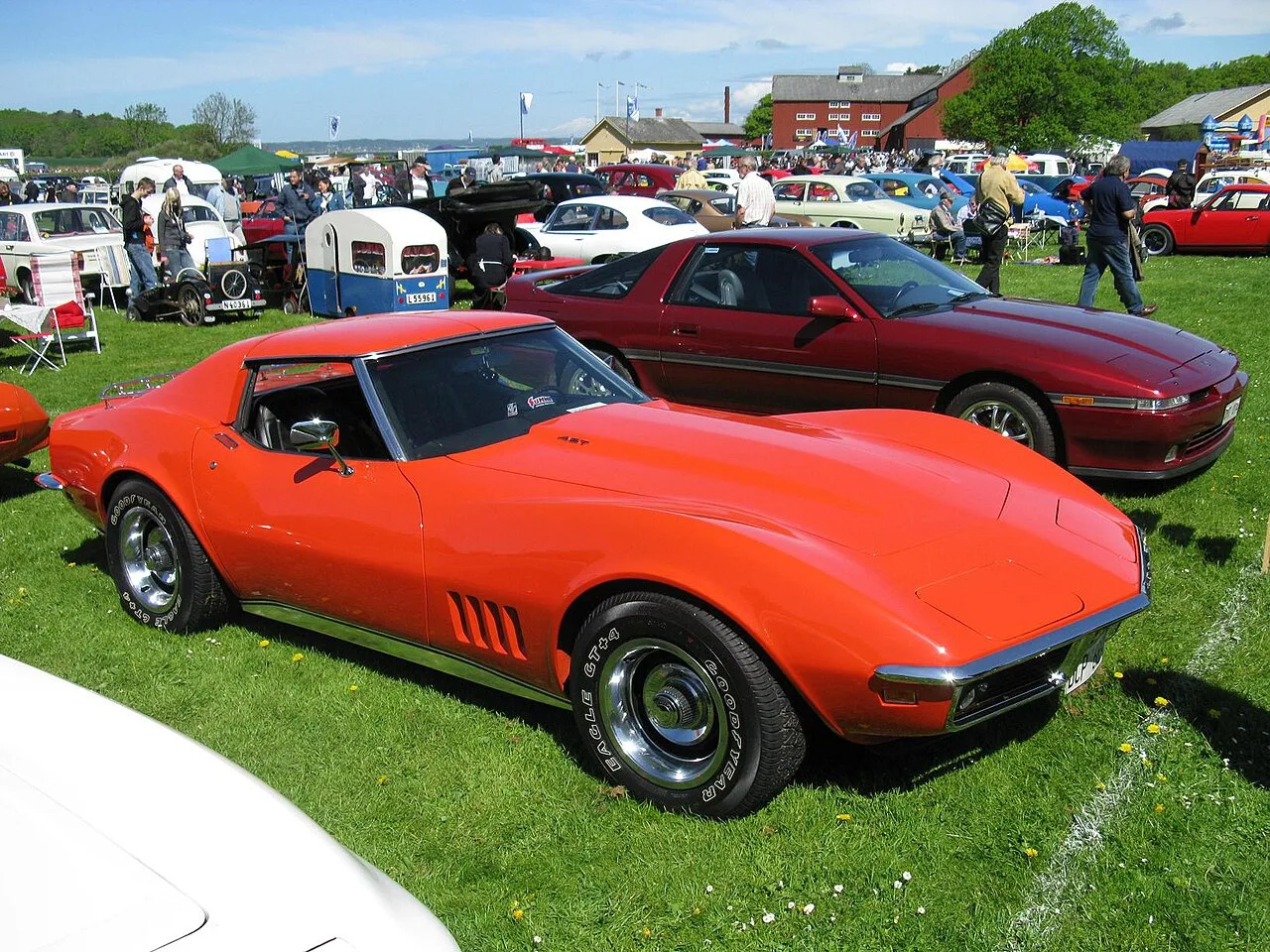 Een oranje Chevrolet Corvette C3 uit het 1968-1969 tijdperk op een autoshow